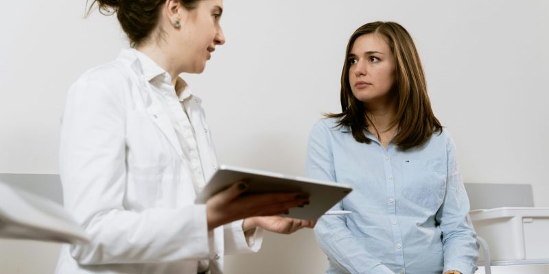A doctor consults with a pregnant patient discussing healthcare options in a medical facility.